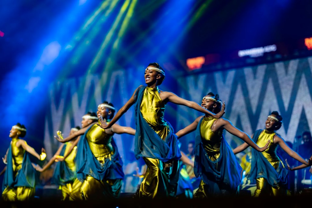 Traditional dancers in gold and blue performing under stage lights