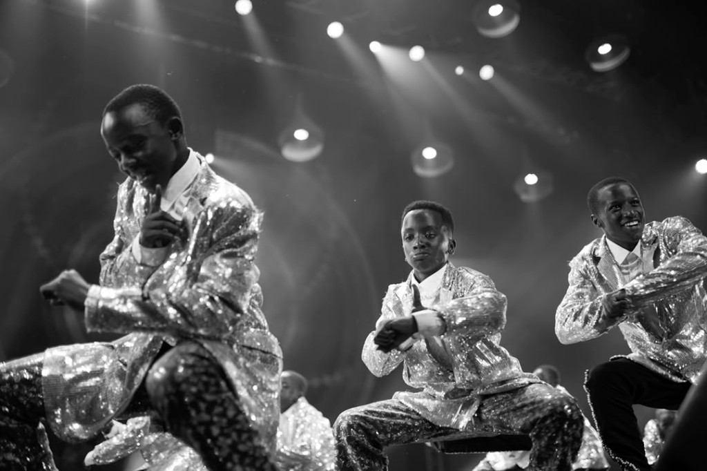 Young boys performing an energetic dance in sequined suits on stage