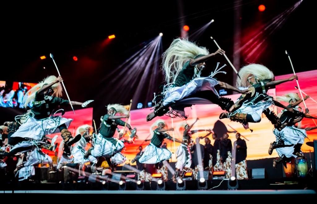 Intore dancers leaping on a professional stage with dramatic lighting